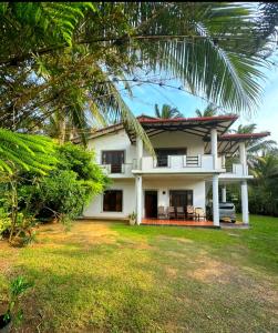 a white house with a palm tree in front of it at Royal beach villa in Unawatuna