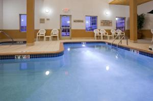 a large swimming pool in a hotel room with chairs at Grandstay Apple Valley in Apple Valley