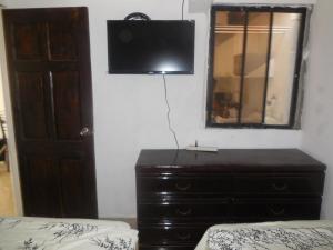 a bedroom with a dresser with a television on the wall at Condominio Tropical villa 2 in Jacó
