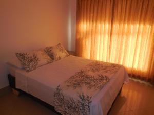 a bedroom with a bed and a window with curtains at Condominio Tropical villa 2 in Jacó