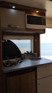 a kitchen with a stove and a sink in an rv at שלווה בים - צימר ים המלח, deadsea in Ovnat