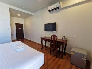 1 dormitorio con 1 cama y escritorio con TV en โรงแรมรชาโขง Racha Khong Hotel, en Nakhon Phanom