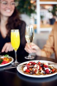 una mujer sentada en una mesa con un plato de comida y copas de vino en Zoku Amsterdam en Ámsterdam