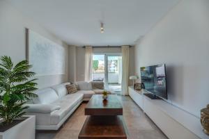 a living room with a white couch and a tv at VACATION MARBELLA I Via Celere, Huge Terrace, Brand New Complex, Close to the Beach, Marbella Center in Marbella
