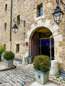 une entrée à un bâtiment avec deux plantes en pot dans l'établissement Hôtel Le Château Fort de Sedan, à Sedan