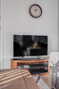 a living room with a tv and a clock on the wall at Cosy countryside apartment in Wellingborough