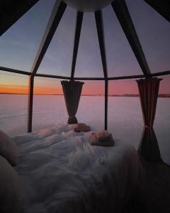 a bed in a tent with a view of the ocean at Ylläsjärvi iglu in Ylläsjärvi