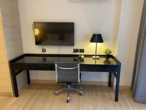 a desk with a television and a chair in a room at Melaka The Straits Residence in Melaka