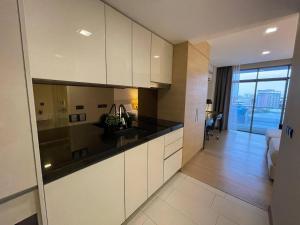a kitchen with white cabinets and black counter tops at Melaka The Straits Residence in Malacca