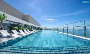 hotelowy basen z białymi krzesłami i oceanem w obiekcie CĂN HỘ CONDOTEL 5 SAO THE SONG VŨNG TÀU - Apartment 5 Star Luxury The Song Vung Tau w mieście Vung Tau