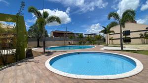 two swimming pools in a courtyard with palm trees at Apides Palace Hotel Ltda in Pedro Canário