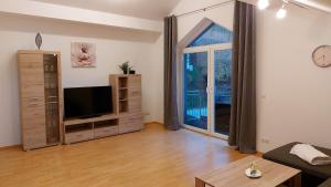ein Wohnzimmer mit einem TV und einem großen Fenster in der Unterkunft Ferienwohnung Tina in Breitenberg