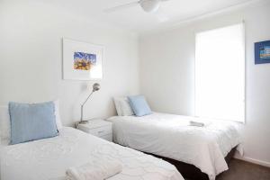 Un dormitorio con dos camas y una ventana en Beachfront Six, en Mollymook 11 fotos más