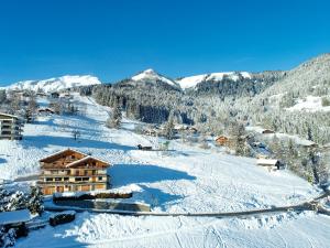 a ski lodge on a snowy hill with snow covered mountains at Chalet Les Rhodos in Cordon