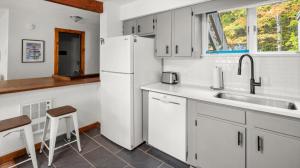 La cuisine blanche est équipée d'un évier et d'un réfrigérateur. dans l'établissement 57 North Lynx Condo Condo, à Warren