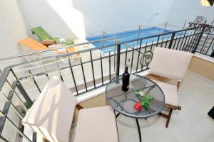 a glass table with a bottle of wine on a balcony at Apartments Villa Tomislav in Brela