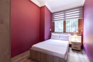 um quarto com paredes roxas e uma cama com uma janela em Charming Flat near Kennedy Avenue in Fatih em Istambul