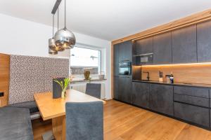uma cozinha com armários pretos e uma mesa de madeira em Apartmenthaus Maximilian em Neukirchen am Grossvenediger