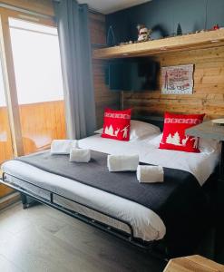 a bedroom with a large bed with red pillows at Chalet Olympie, Appartement avec balcon et vue montagne, ski aux pieds, Méribel-Mottaret in Méribel