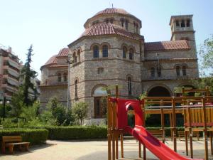 un parque infantil con un tobogán rojo frente a un edificio en Το σπίτι της Περσεφόνης, en Atenas