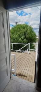 an open door to a deck with a view of a bush at Departamento en Trelew in Trelew