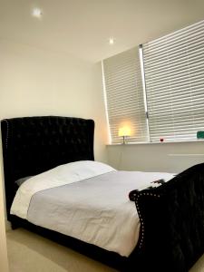 una camera da letto con letto con testiera nera e finestra di Comfort Stay Apartment - Haywards Heath a Haywards Heath