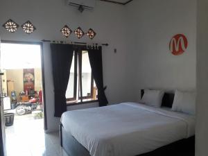 a bedroom with a bed and a large window at Mugeni Homestay in Senggigi