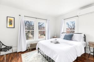 a white bedroom with a bed and two windows at North End Treasure, beautiful 2 bedroom apartment in Detroit