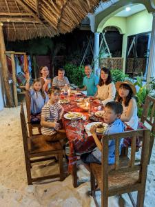 een groep mensen die rond een eettafel zitten bij Mkadi Beach House in Nungwi