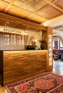 a lobby with a reception counter and a rug at Hotel Hirsch in Oberstaufen