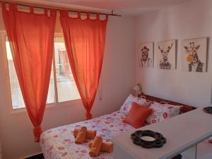 - une chambre avec un lit et une fenêtre avec des rideaux orange dans l'établissement Apartamento Con Encanto 'Larios Studio', à Malaga