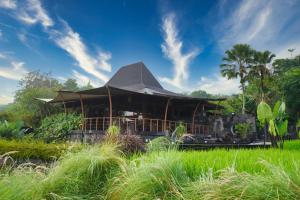a building with a roof in a field of grass at Abhayagiri - Sumberwatu Heritage Resort in Yogyakarta