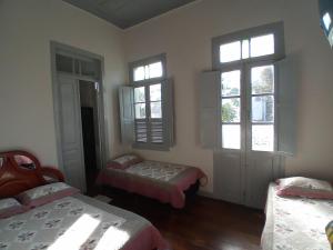 a bedroom with two beds and two windows at Pousada Gameleira in Diamantina