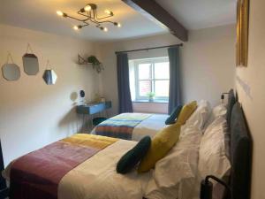 a bedroom with two beds and a window at The Shires - Quirky 3 bed holiday home with Wood-fired Hot-tub in Rudston