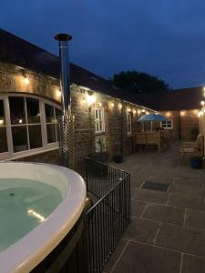 a bath tub in front of a building with lights at The Shires - Quirky 3 bed holiday home with Wood-fired Hot-tub in Rudston