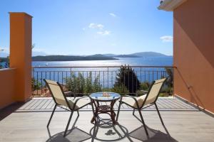Villa Melias, luxurious villa with superb view of the islands, 400 m from the sea في نيدري: شرفة مع طاولة وكراسي وإطلالة على المحيط