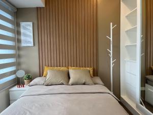 a bedroom with a large bed with a wooden headboard at Homey 1 Bedroom Unit at Air Residences in Manila