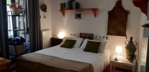 a bedroom with a bed with white sheets and green pillows at La Casa del Pittore di Petralia in Petralia Soprana