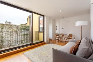 een woonkamer met een bank en een groot raam bij ALTIDO Vitoria apartments near the Cathedral in Porto