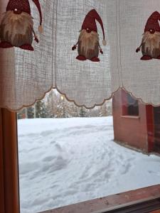 a window with santa claus decorations on the curtains at La Casa degli Gnomi in Falcade