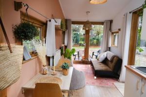 een woonkamer met een tafel en een bank bij Tiny House Hilver - uniek en sfeervol huisje middenin het bos in Diessen