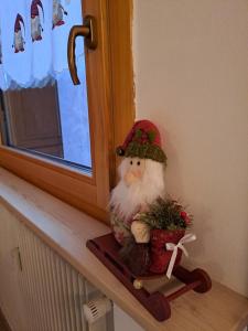 a santa claus figurine sitting on a window sill at La Casa degli Gnomi in Falcade