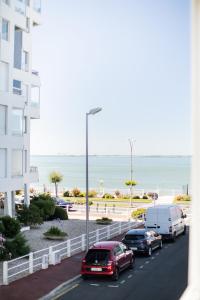 a street with cars parked next to a building and the ocean at le Foncillion in Royan