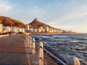 a boardwalk on the beach next to the ocean at Beach Road Studio in Cape Town