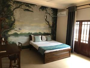 モラトゥワにあるAmani Lake Resortのベッドルーム1室(壁に絵画が描かれたベッド1台付)