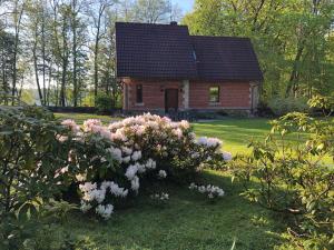una pequeña casa con flores rosas delante en Mednieku Namiņš en Sigulda