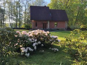 uma pequena casa com flores cor-de-rosa em frente em Mednieku Namiņš em Sigulda