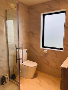 a bathroom with a toilet and a window at Modern & Luxurious Home 2 in Auckland