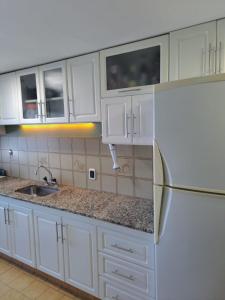 Una cocina con gabinetes blancos y un refrigerador. en Vision2000, en Bahía Blanca
