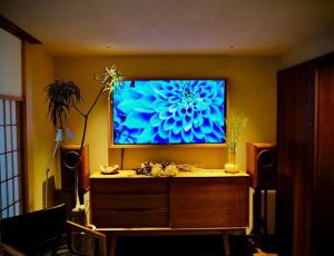 uma sala de estar com uma grande televisão na parede em 萌蘖　露天風呂とサウナがある現代の湯治場 em Kagoshima